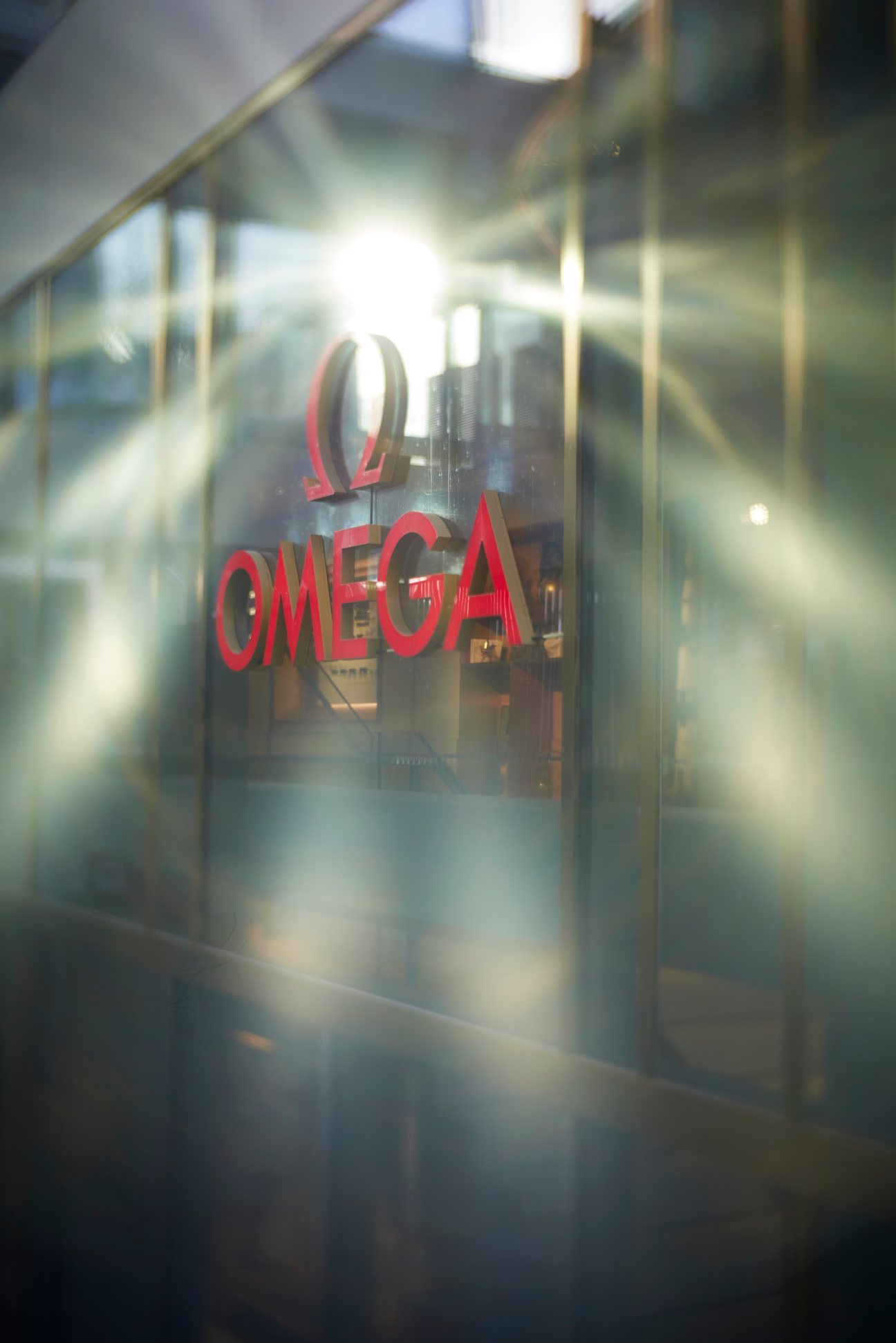 Blurred view of Omega store entrance with red Omega logo and symbol visible on glass storefront