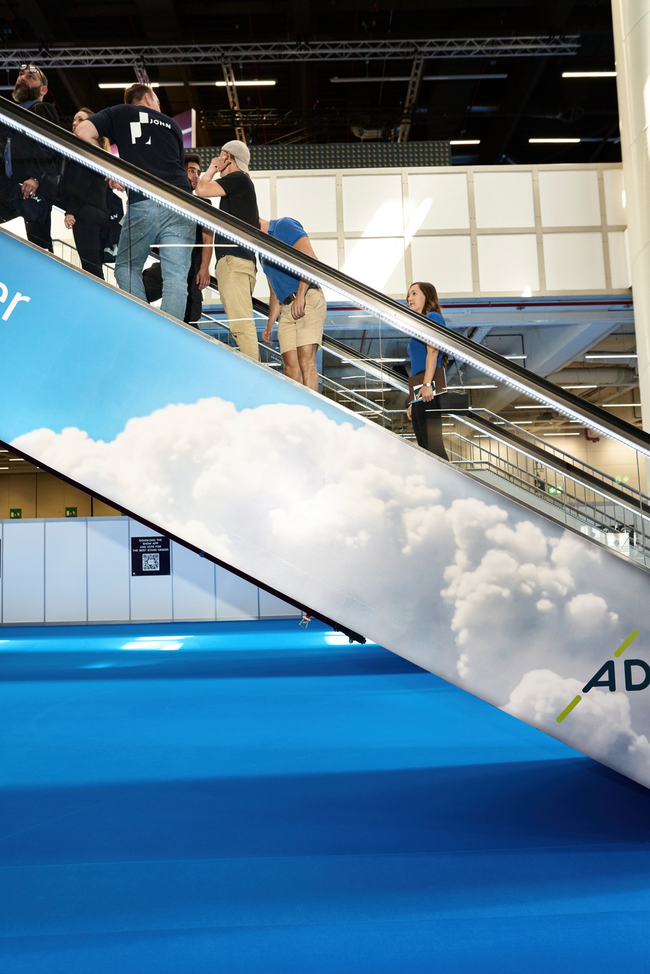 Attendees ascending airplane stairs at Aircraft Interiors Expo in Hamburg, with blue aircraft fuselage and cloud graphics visible