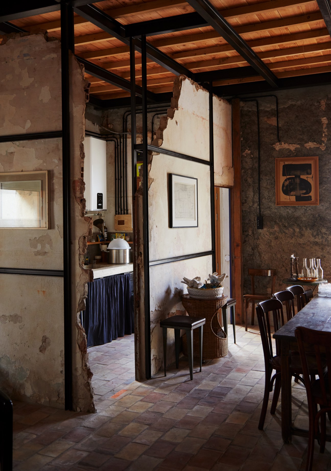 Rustic interior with exposed wooden beams, weathered walls, terracotta floors and steel framework in Mediterranean cabin