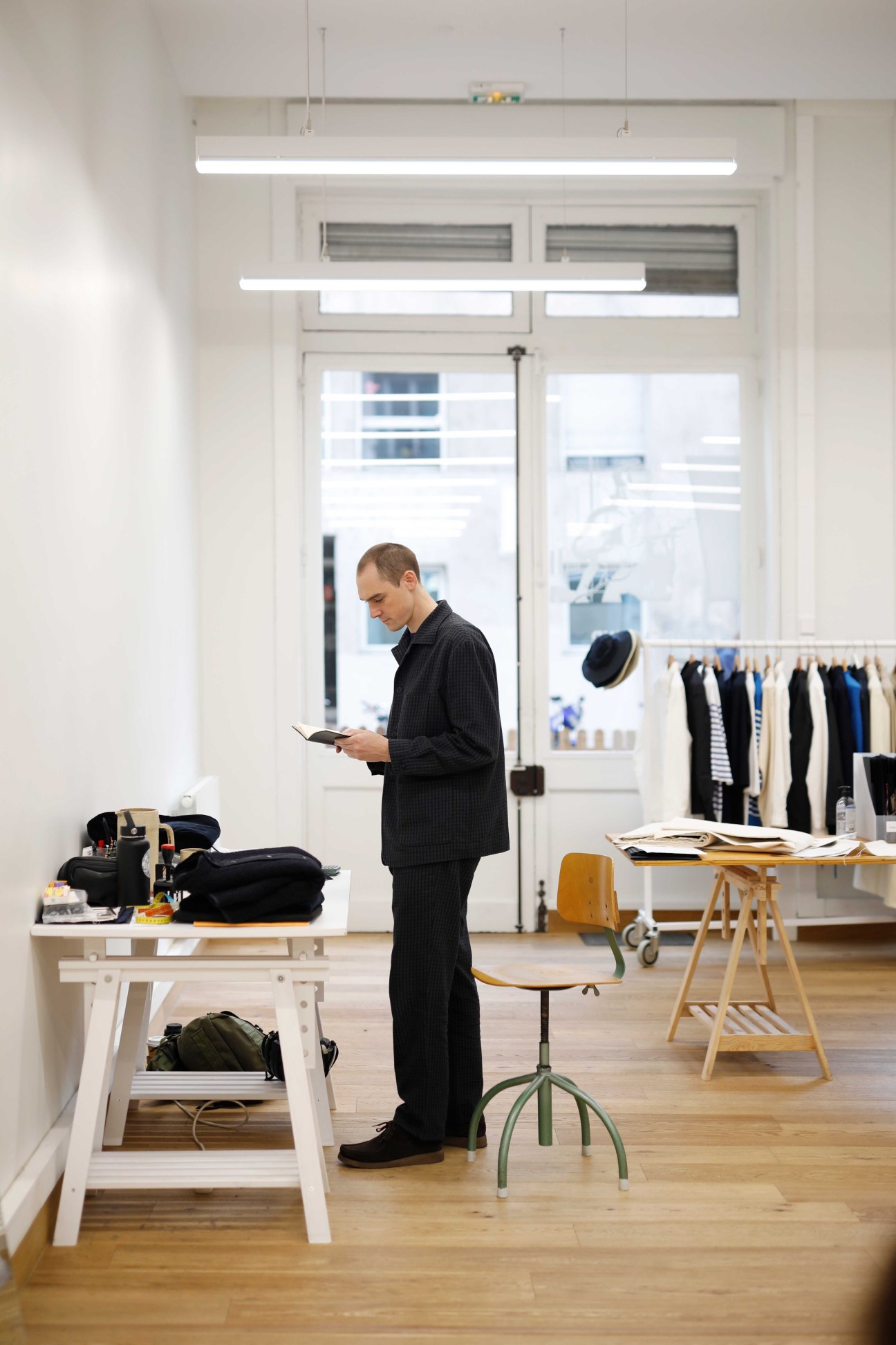 Man in black pinstripe suit browsing clothing in Arpenteur shop in Lyon