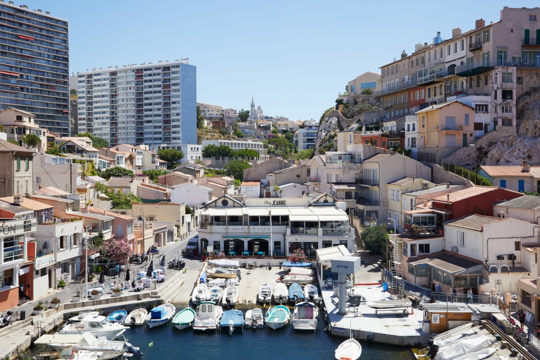 Small harbor with fishing boats and colorful buildings built into rocky cliffs in Vallon des Auffes