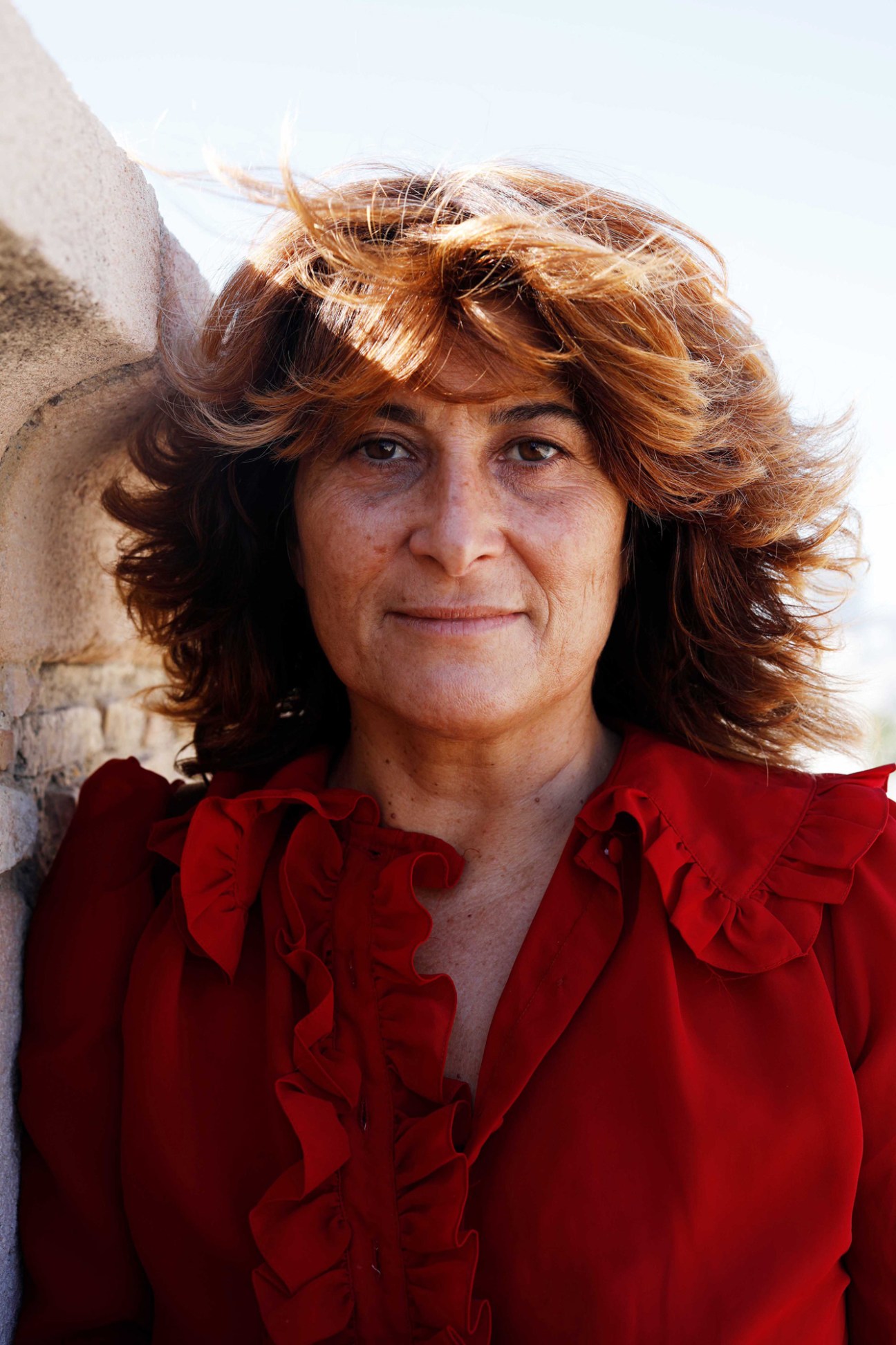 Isabelle Crampes, founder of shop De Toujours, wearing red blouse with ruffles standing outdoors