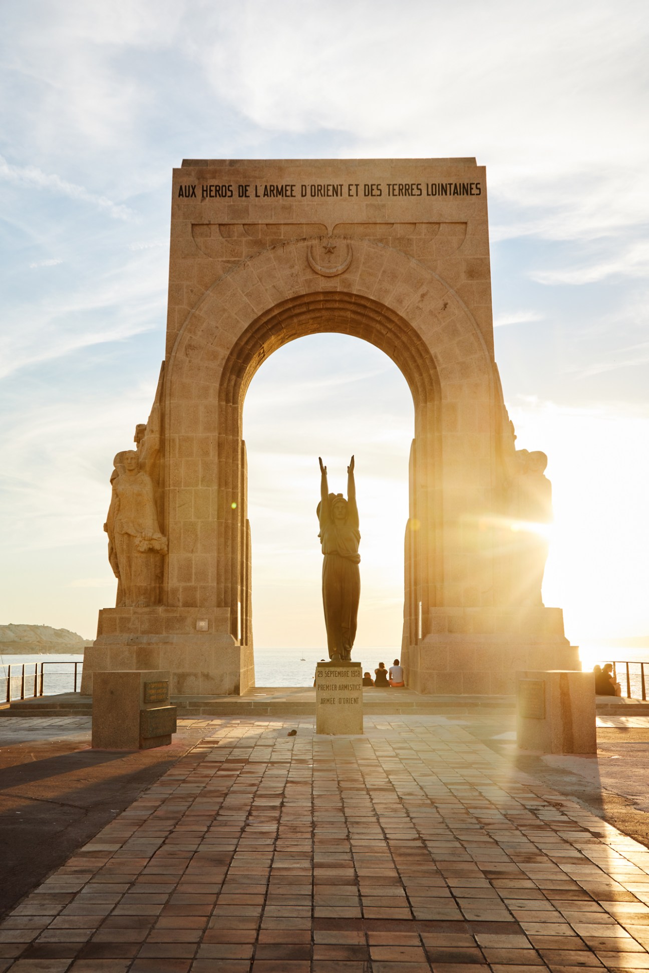 Stone archway monument La Porte de L'Orient Monument aux Armées d'Afrique at sunset with silhouetted statue