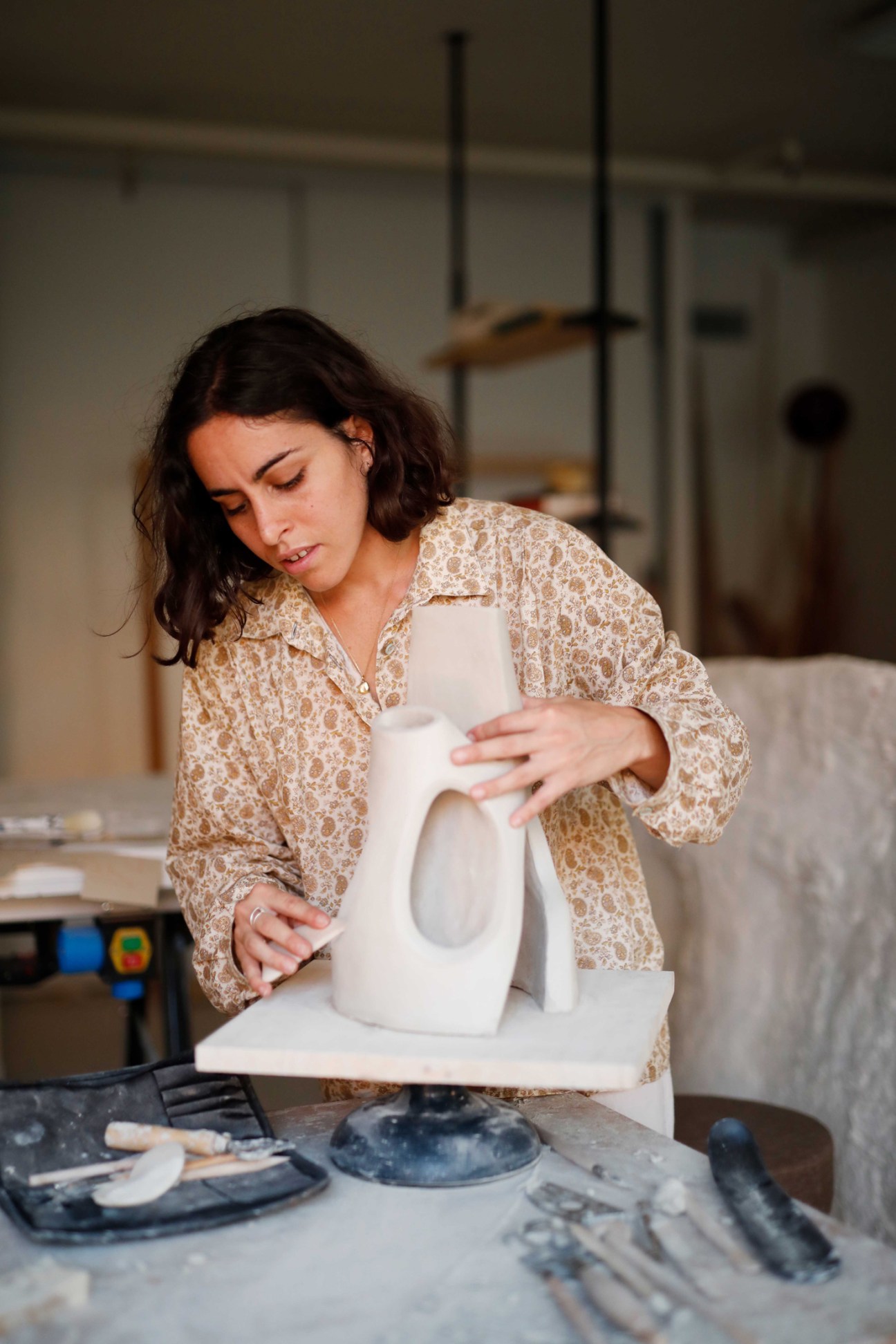 Artist Léa Bigot working on a white ceramic sculpture in her studio