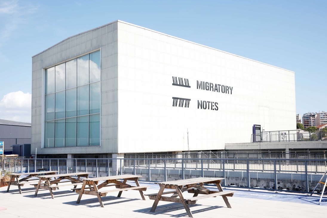 Outdoor terrace with wooden picnic tables at cultural center overlooking cityscape