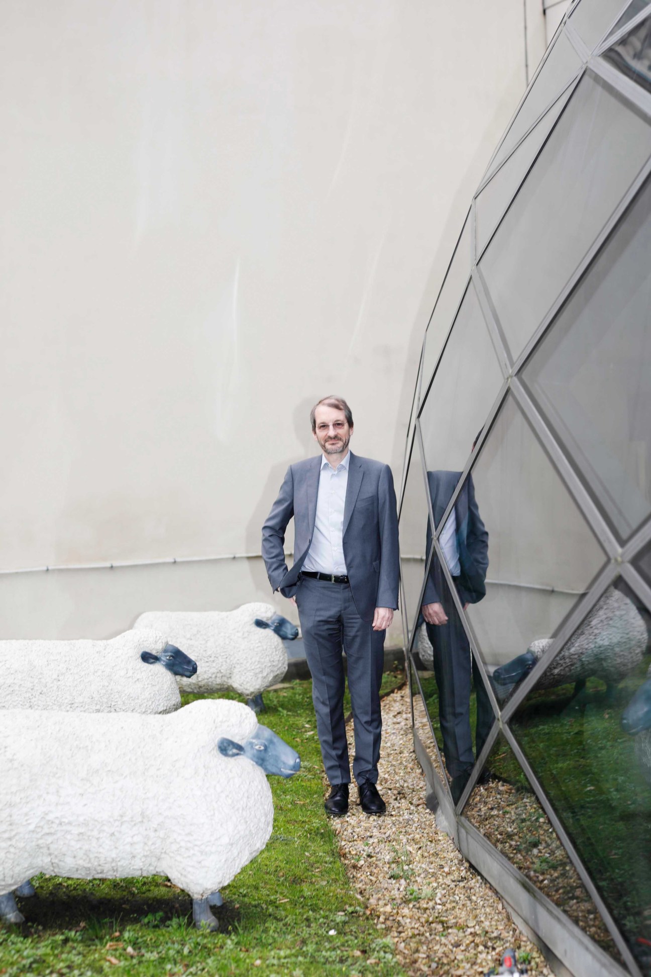Dag Rasmussen standing next to decorative white sheep sculptures and modern glass building facade
