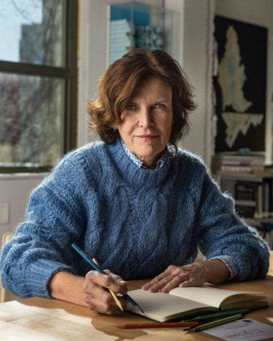 Portrait of Jeanne Gang seated in her Chicago studio, surrounded by architectural models and materials