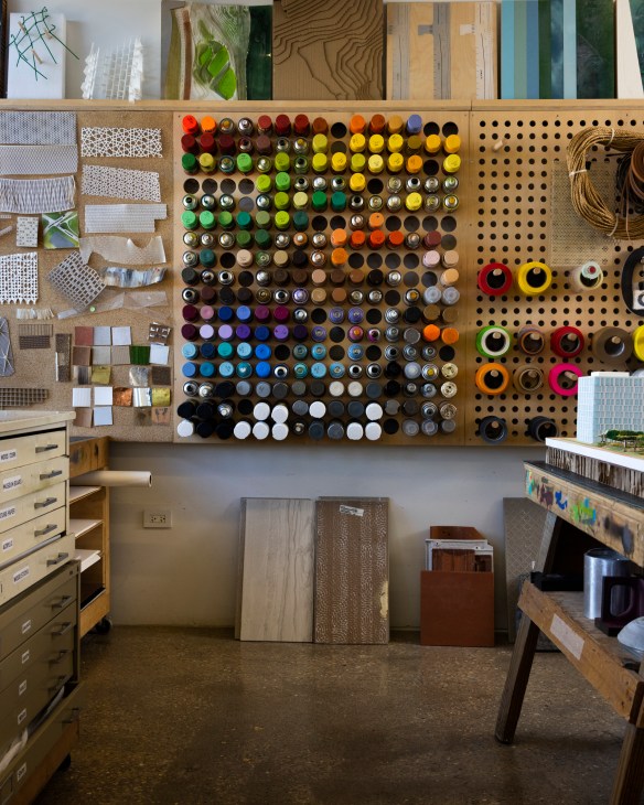 Various model-making tools and supplies including cutting implements, adhesives, and small construction materials organized on a work surface