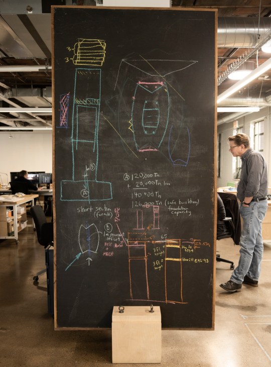 Technical design diagrams and sketches showing architectural concepts and spatial relationships spread across a work table
