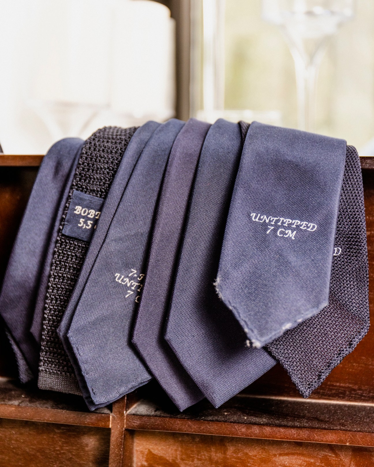 Collection of navy blue neckties with text labels arranged on a wooden surface