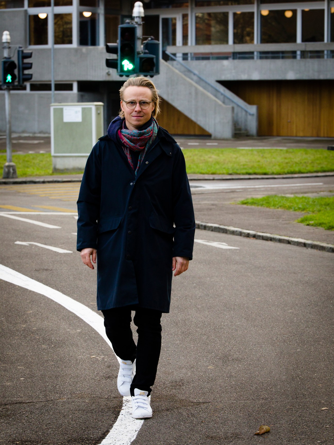 Portrait of Swiss architect Lukas Raeber standing on a street wearing glasses and a dark coat
