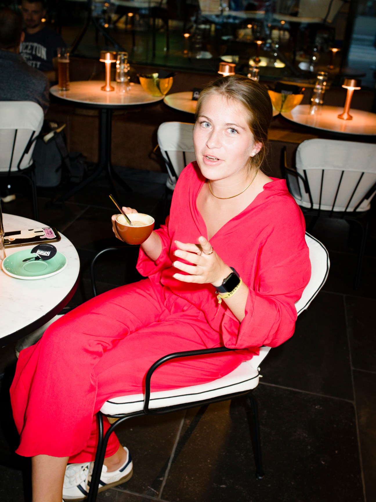 Woman in red dress enjoying coffee at nzz am Bellevue restaurant with modern table settings