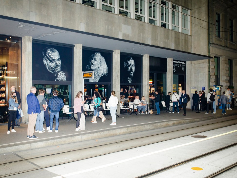 Large black and white portrait photographs displayed in the windows of nzz am Bellevue restaurant