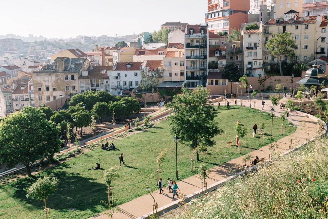 Aerial view of a green park with trees, pathways, and visitors surrounded by Lisbon residential buildings.