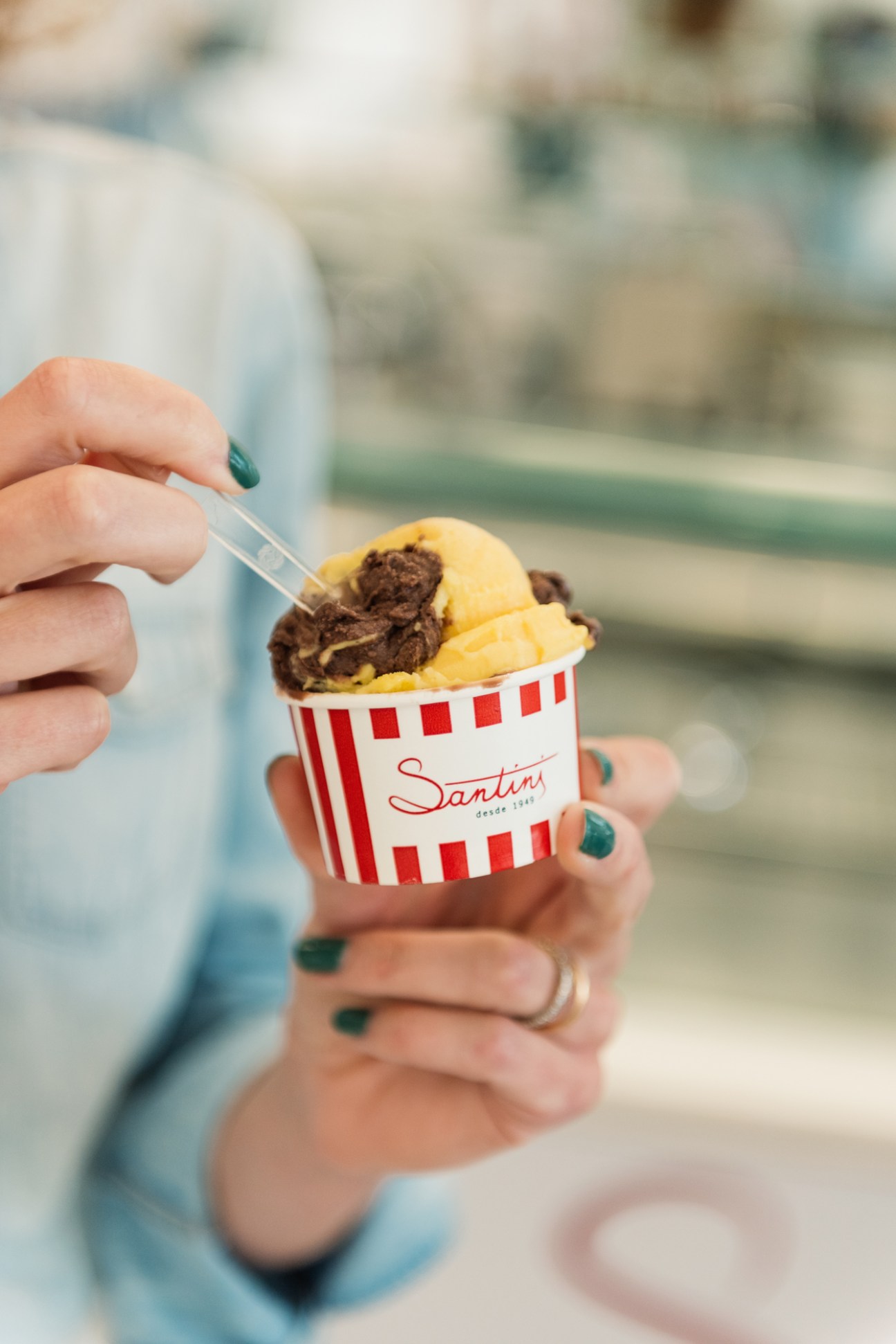 Hand holding a Santini gelato cup with vanilla and chocolate gelato scoops.