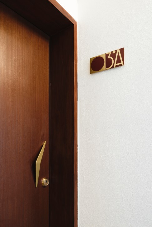 Wooden door with brass handle and geometric room number sign at The Modernist hotel in Faro.