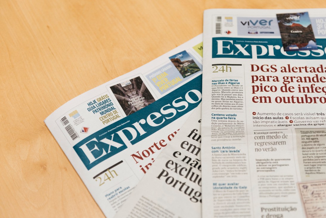 Portuguese newspapers displayed on wooden surface showing Expresso publication with headlines and articles