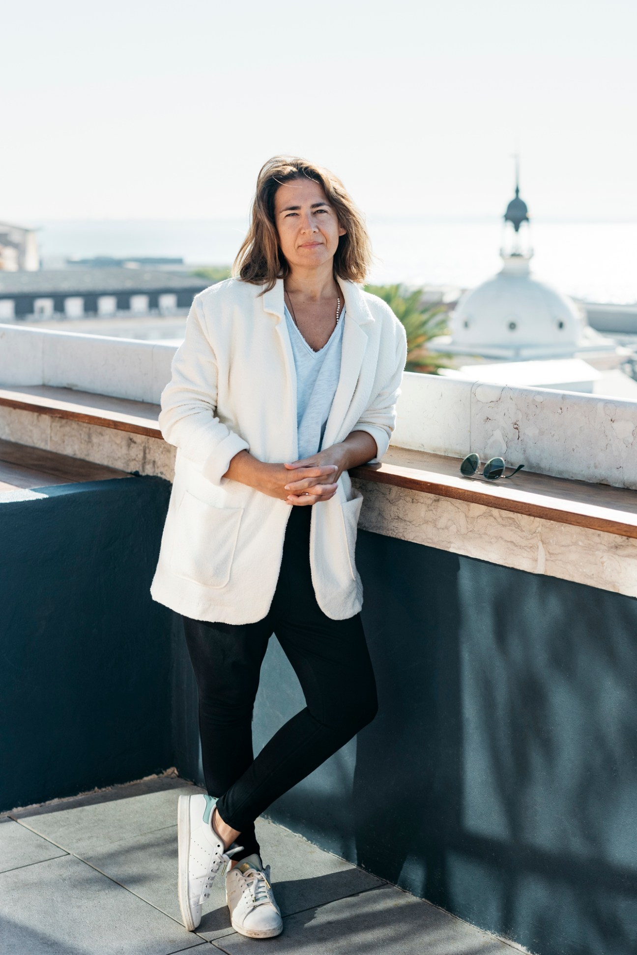 Portrait of Portuguese director Patrícia Sequeira standing on a rooftop terrace in white blazer