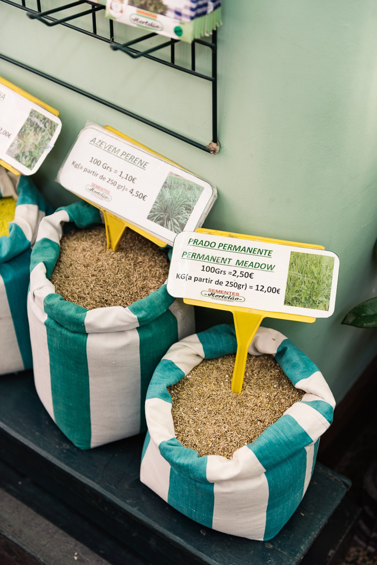 Bags of seeds with yellow price tags showing permanent meadow varieties in a Portuguese seed shop
