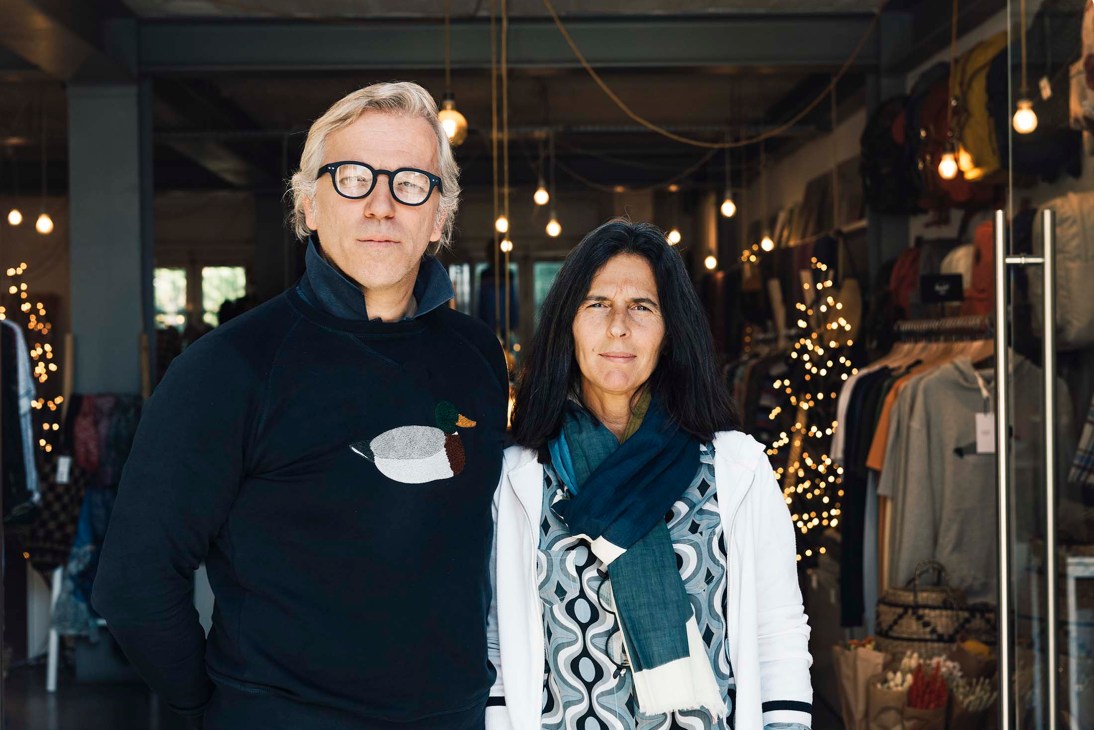 Alexandra Bernardo and Tiago Leiria Miranda stand in their retail store decorated with holiday lights.