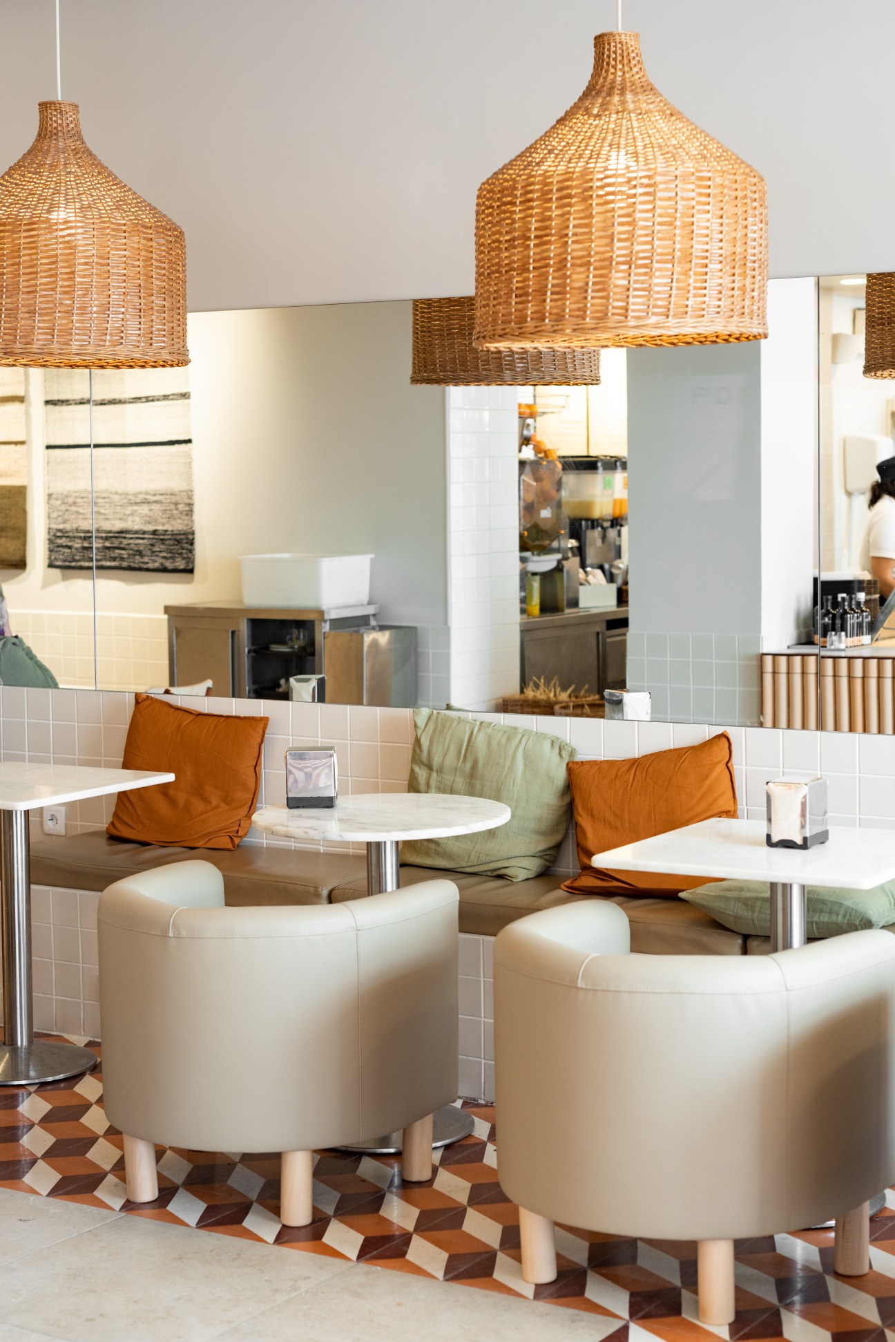 Modern cafe interior with wicker pendant lamps, white round tables, beige chairs and green bench seating