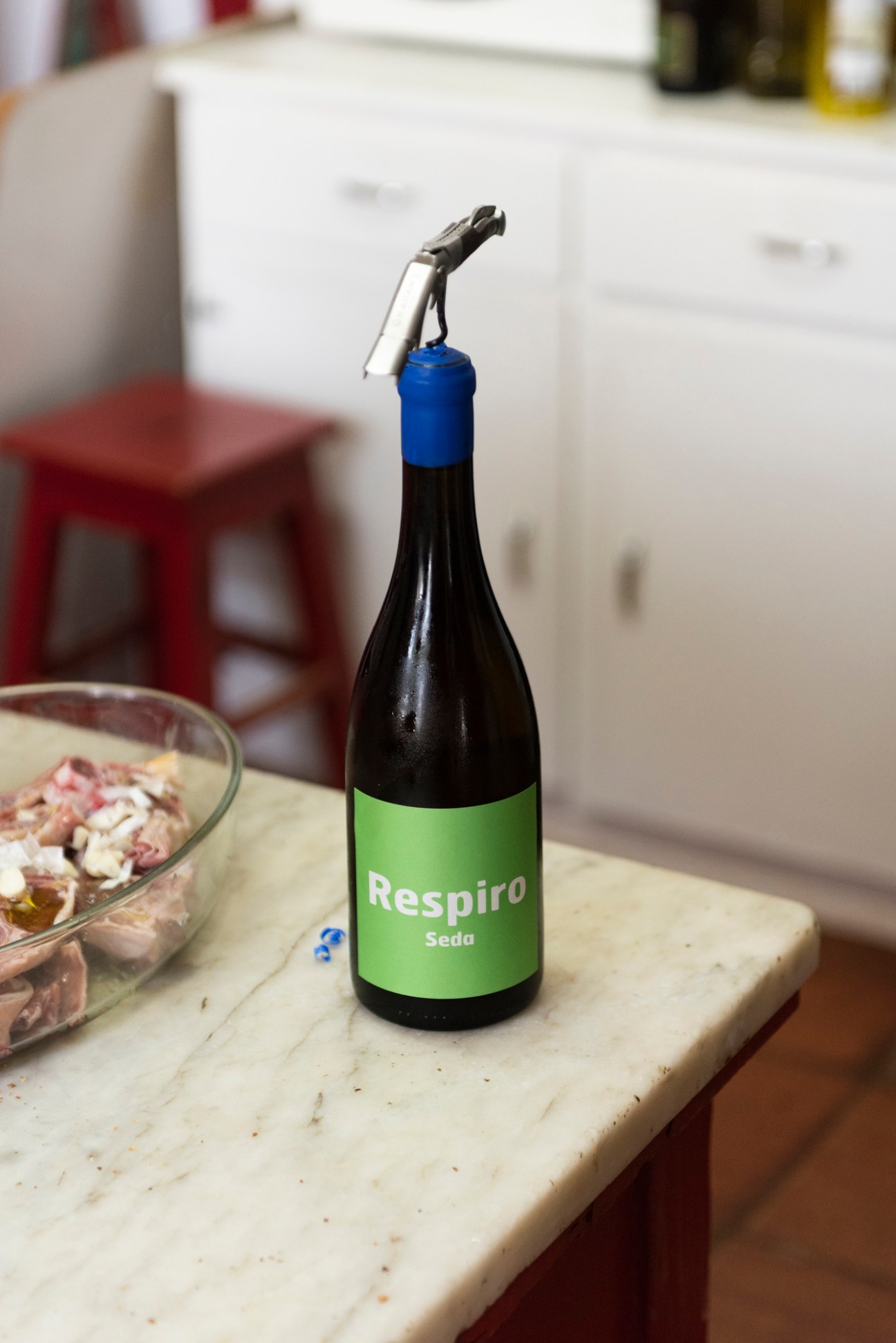 Wine bottle with green Respiro Seda label and wine preservation tool on cutting board next to glass bowl