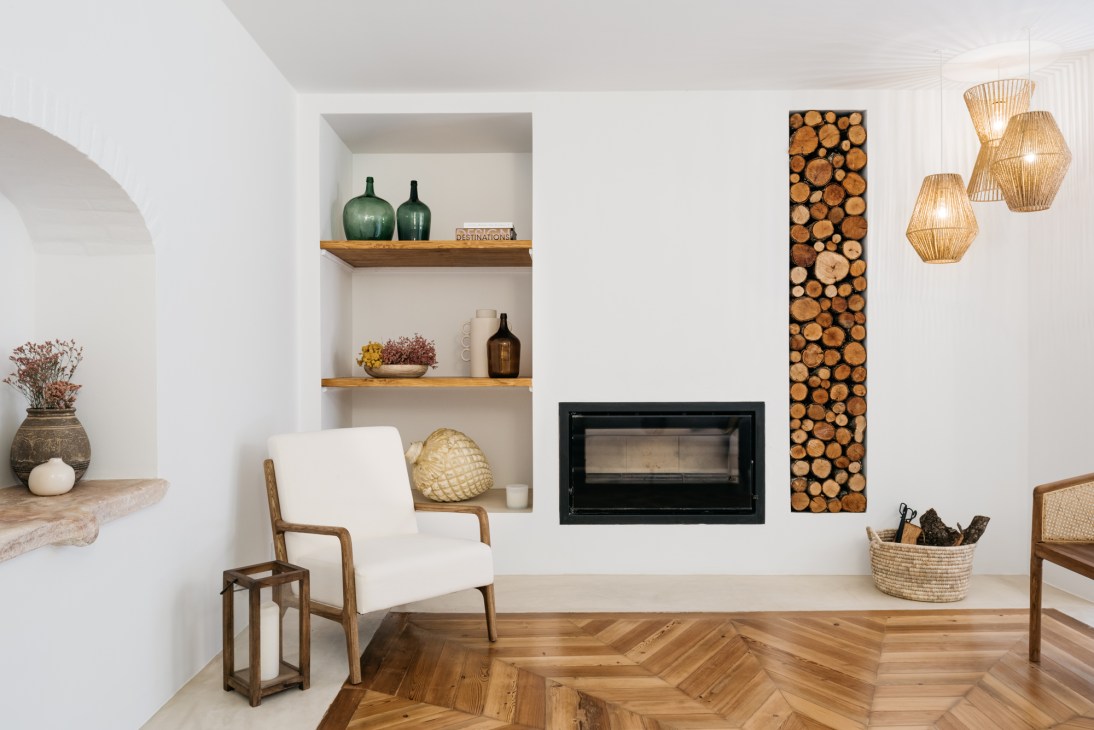 Modern hotel interior with white walls, built-in fireplace, wood storage niche, woven pendant lights and herringbone floors