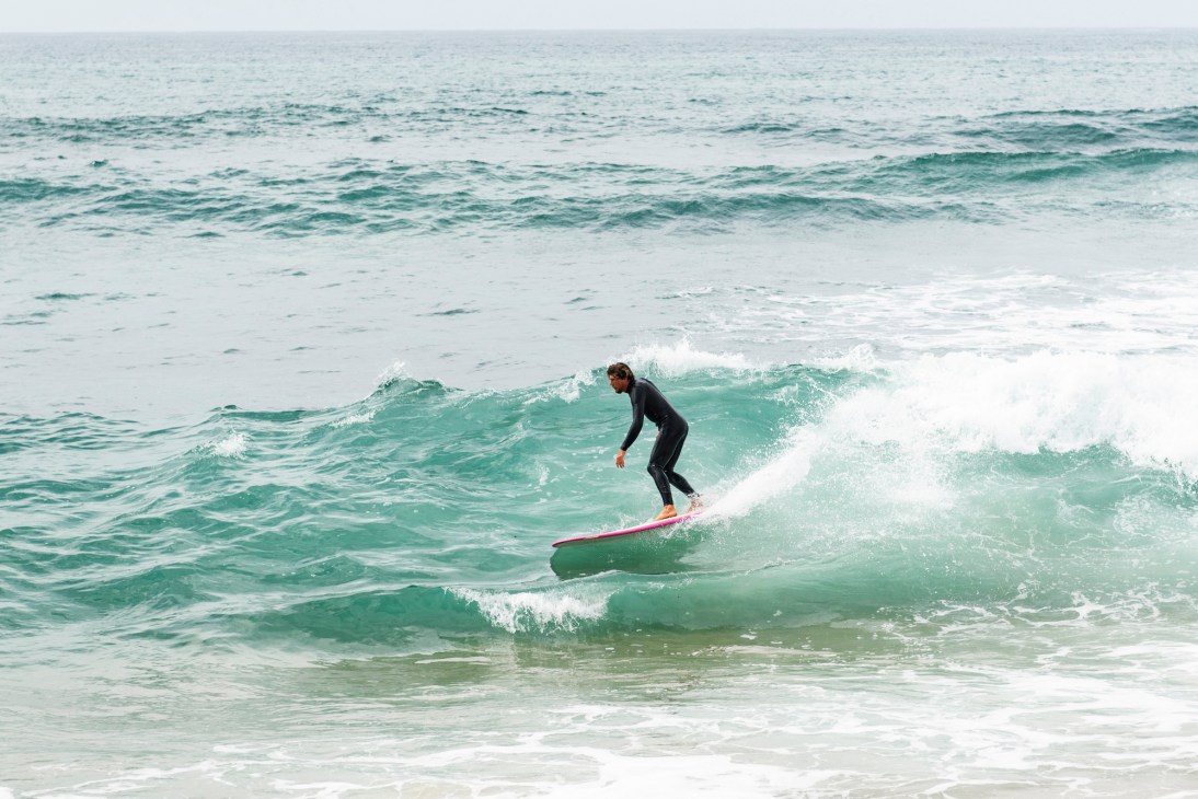 Man in black wetsuit surfing a wave at Ericeira's beach