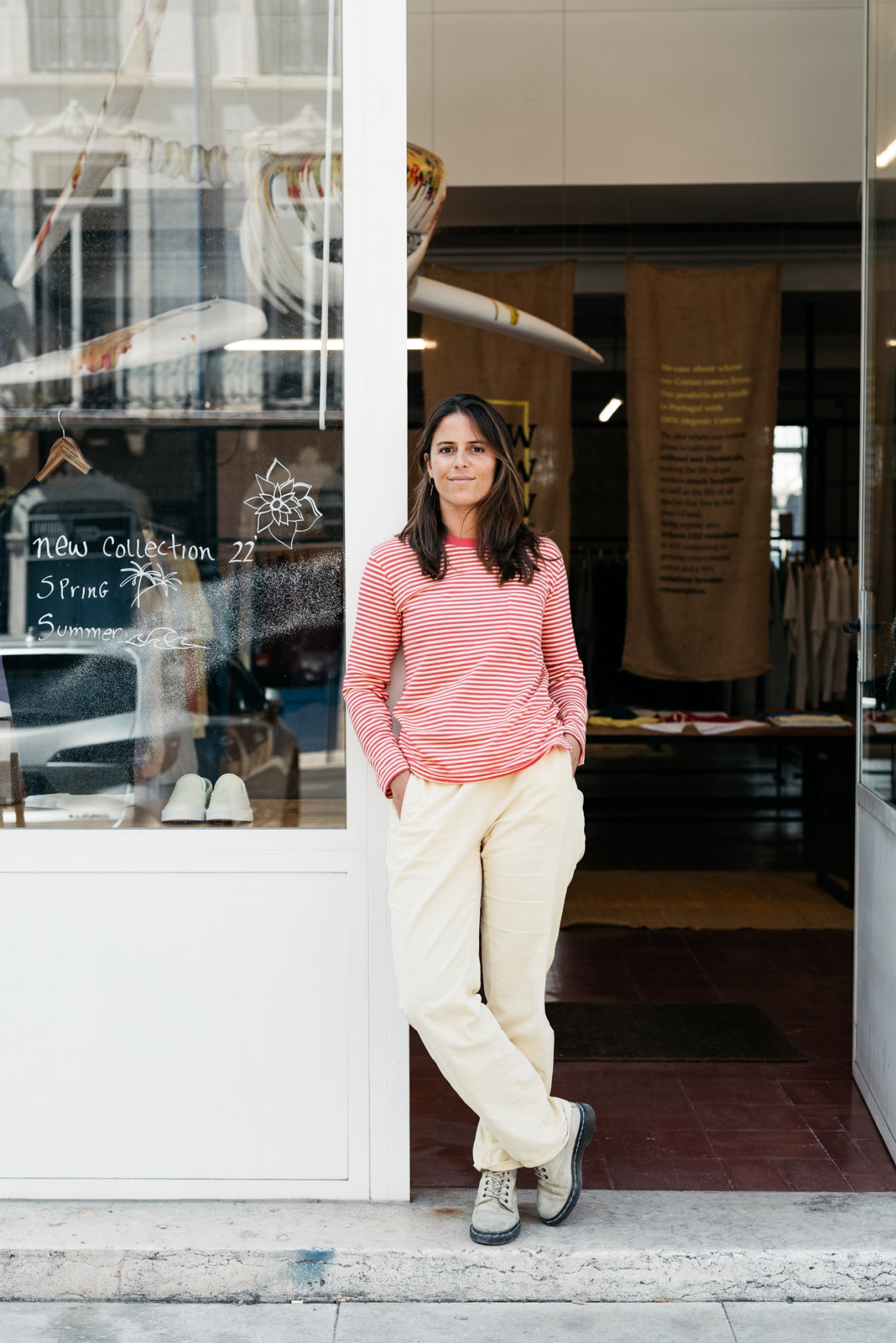Ana Penha e Costa standing in doorway of her store wearing red striped shirt and cream pants