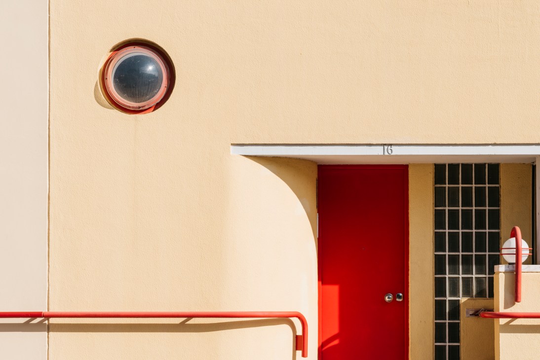Modernist apartment building facade with circular window, red door, and geometric design elements
