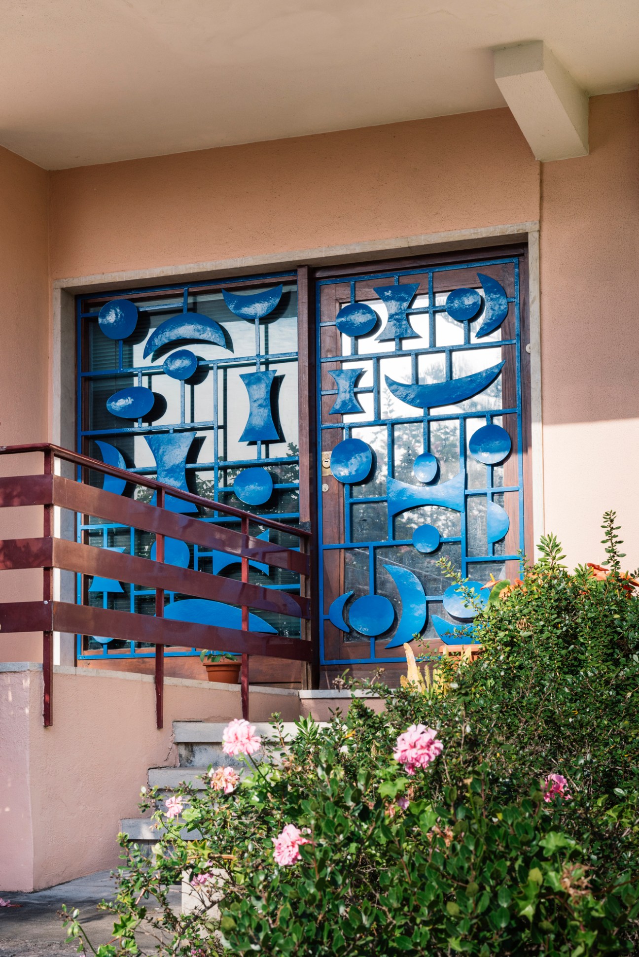 Decorative blue metal scrollwork and geometric patterns on a glass door or window