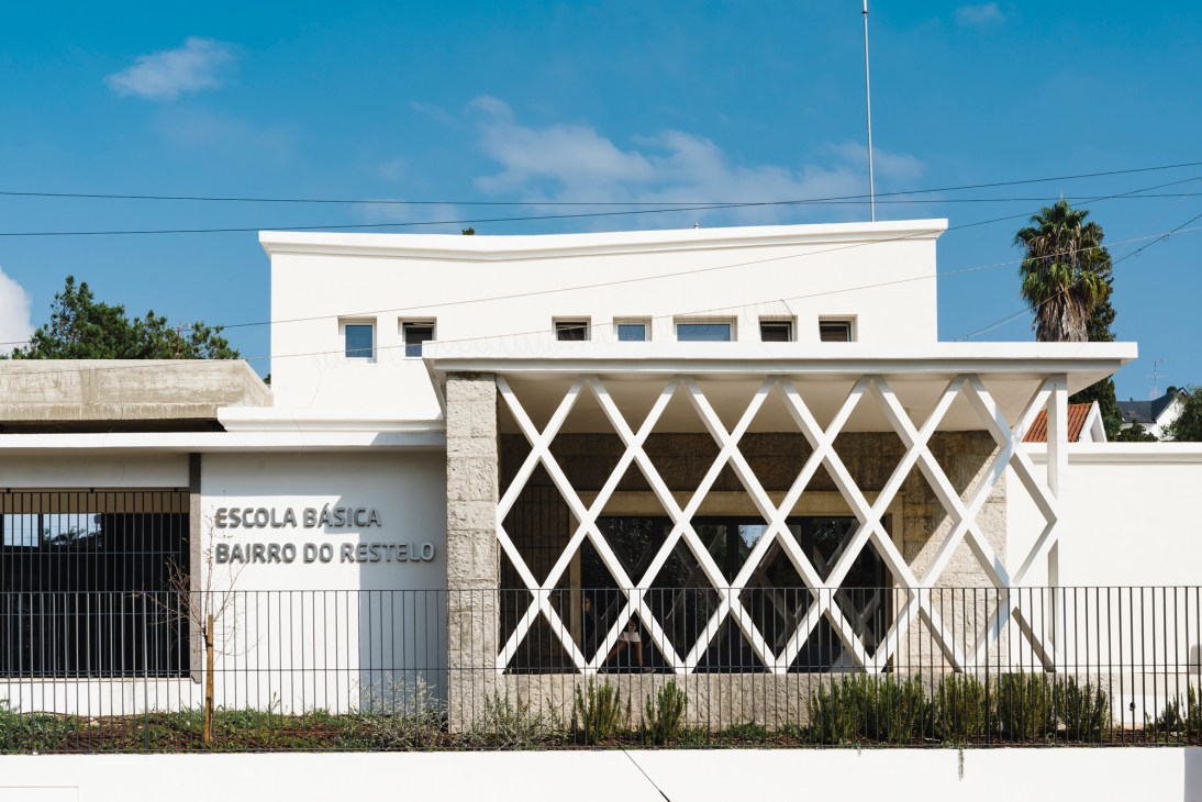 White modern elementary school building with distinctive diamond-patterned lattice facade and flat roof