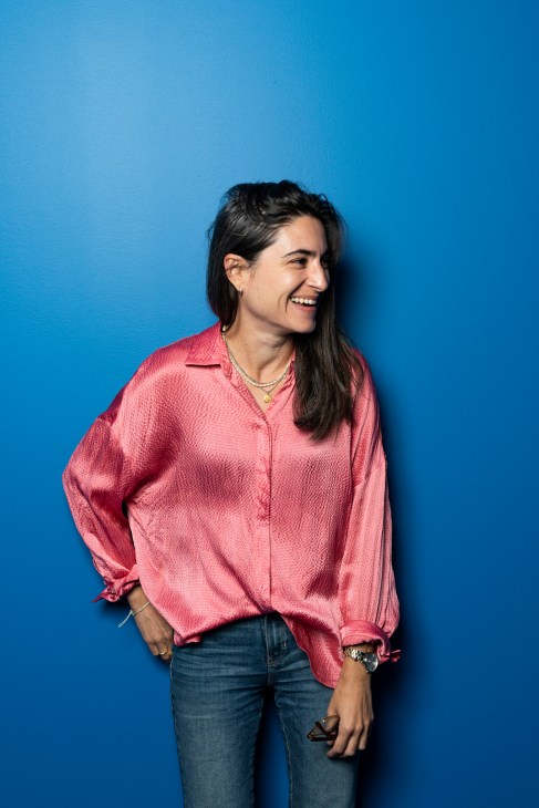 Maria Ramos Silva, editor at Observador, smiling in a pink shirt against a blue background.
