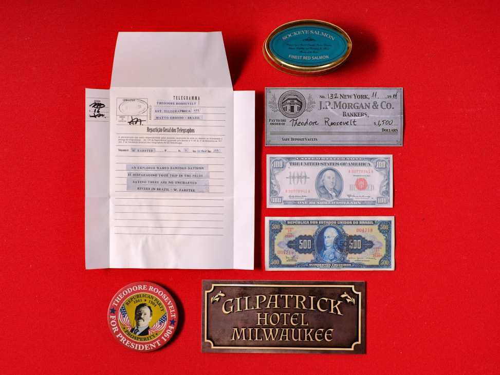 Vintage props including Theodore Roosevelt telegram, J.P. Morgan check, currency, campaign button and hotel sign