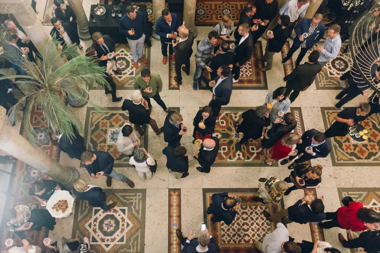 Aerial view of people in business attire mingling at an indoor event on ornate patterned floor