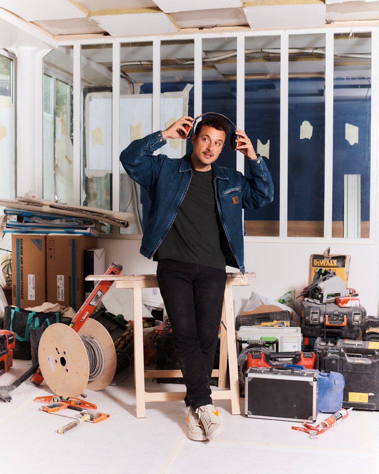 Antoine Bisou wearing headphones in a construction workspace with tools and materials