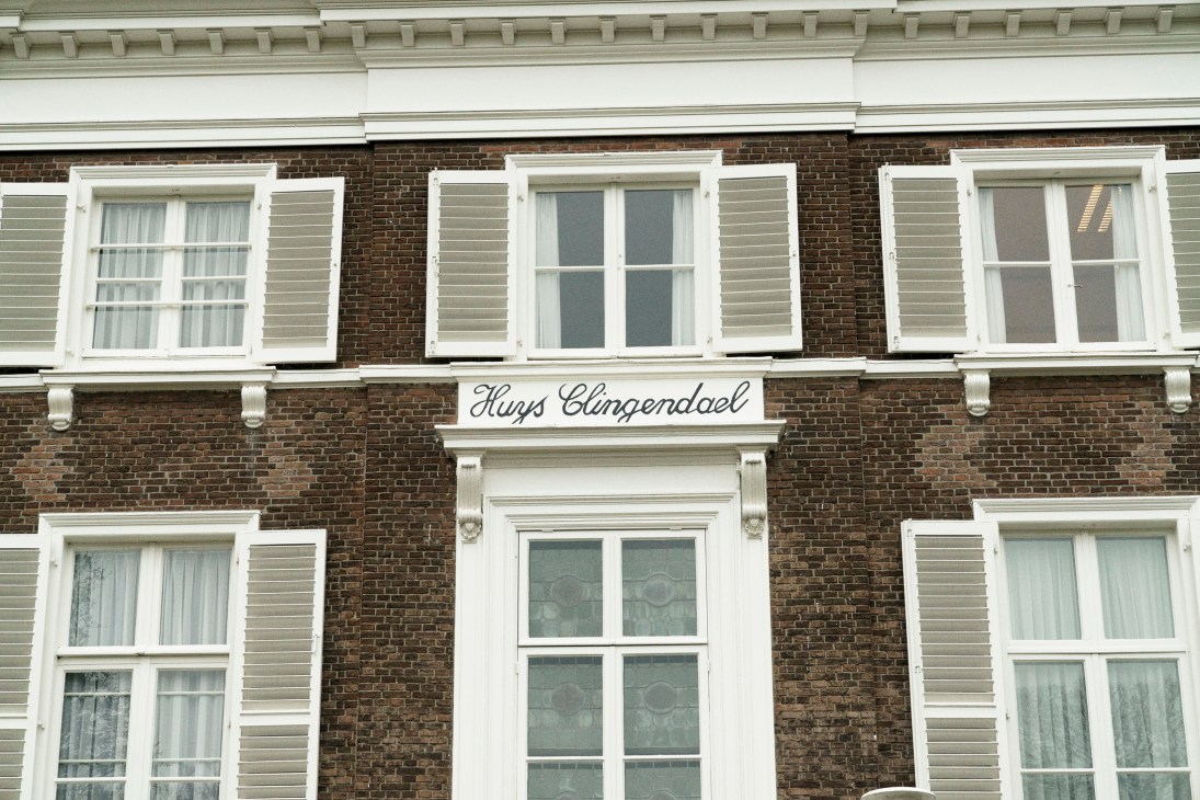 Brick facade of Huys Clingendael, a 17th-century Dutch manor housing the Clingendael Institute, with white-framed windows and shutters.