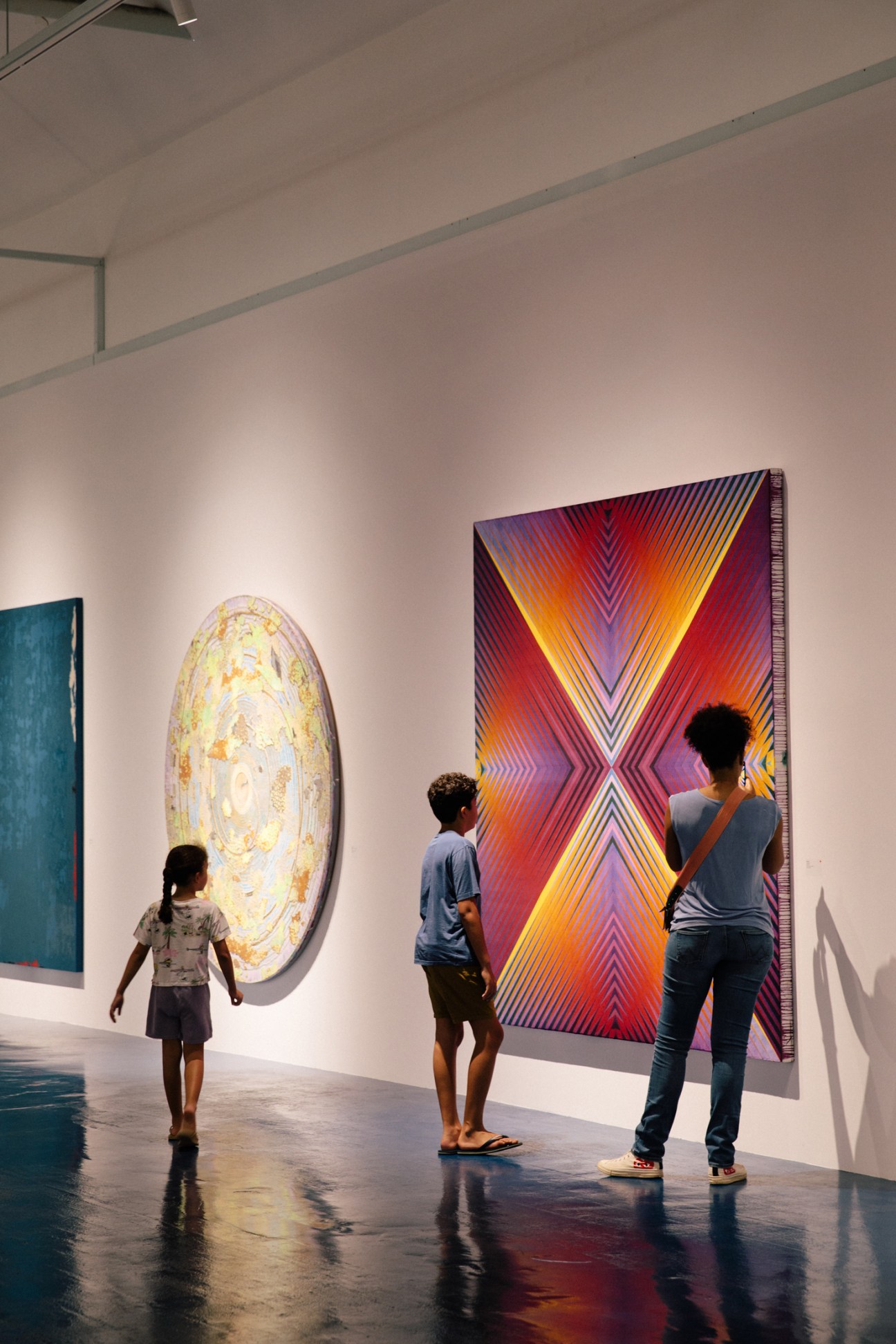 Gallery visitors viewing colorful geometric artwork on white walls in modern exhibition space
