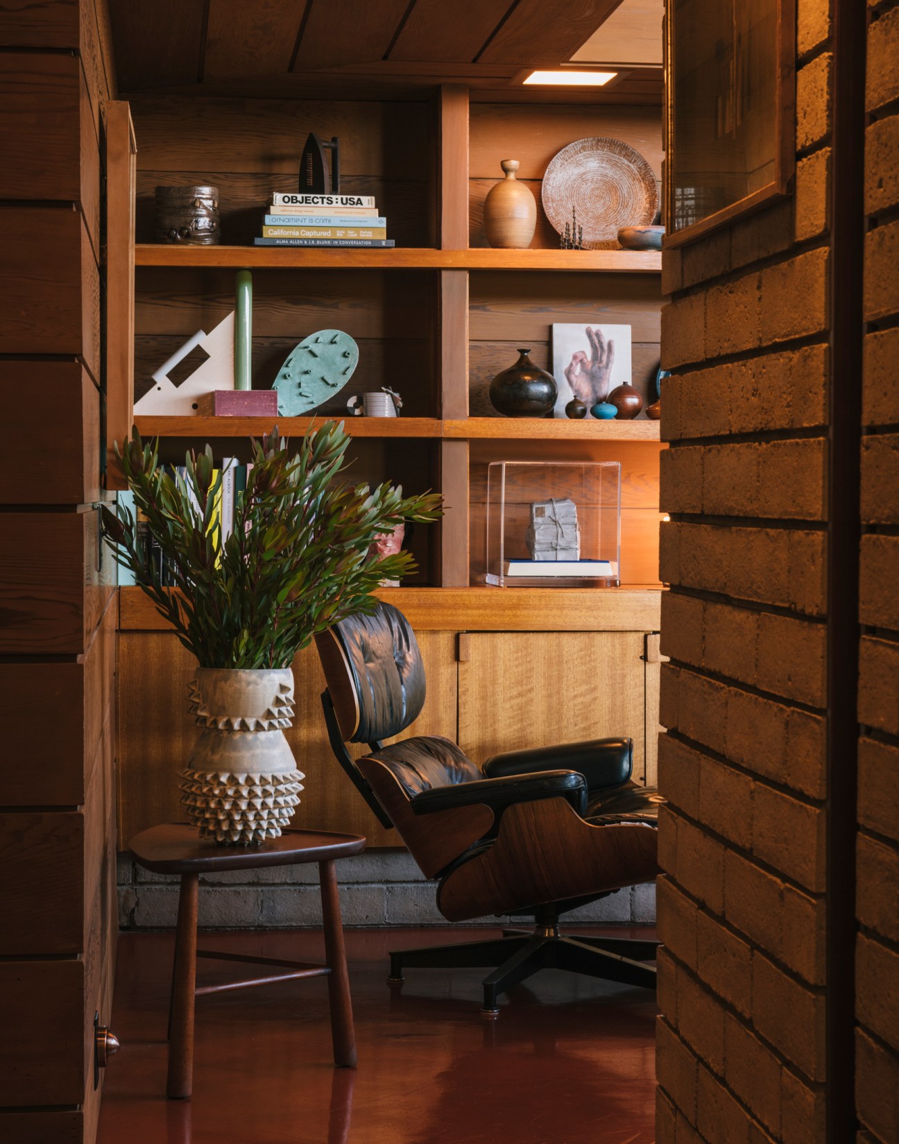 Mid-century modern den with built-in wooden shelving, vintage furnishings, and decorative objects.