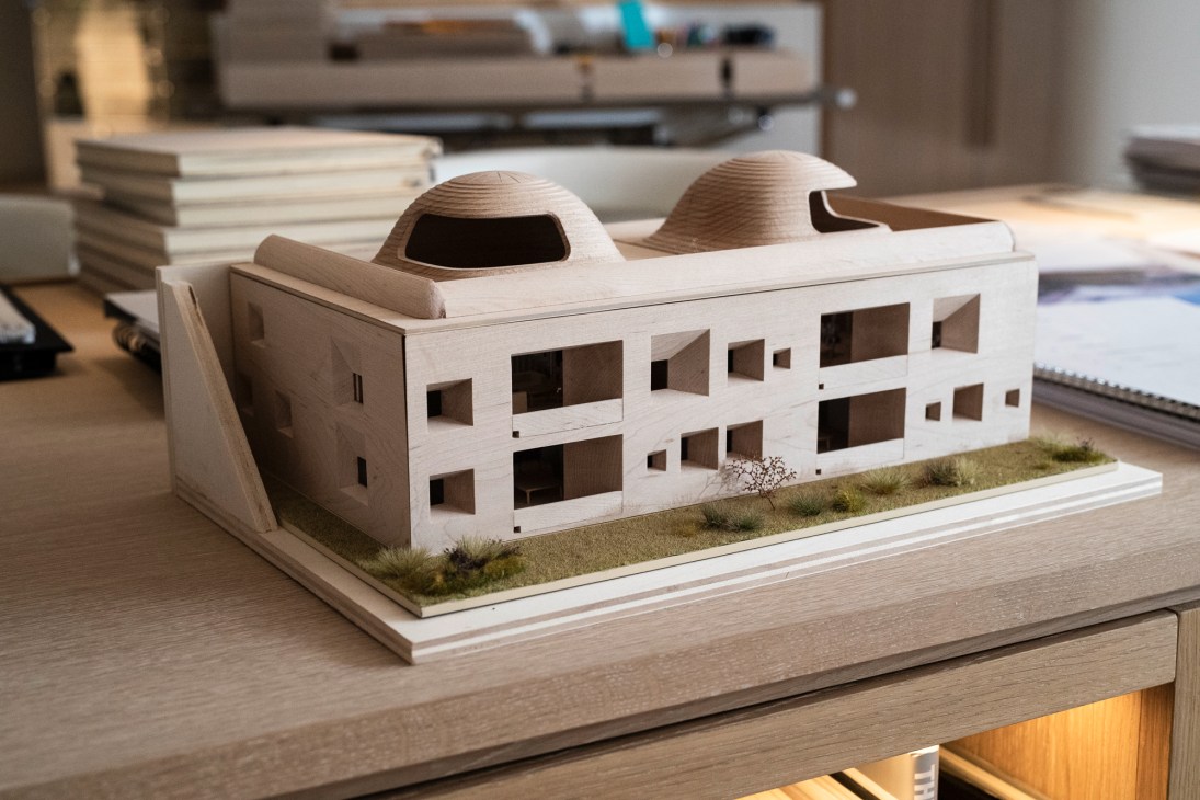 Wooden architectural scale model of Innhub building with distinctive curved roofs and rectangular windows