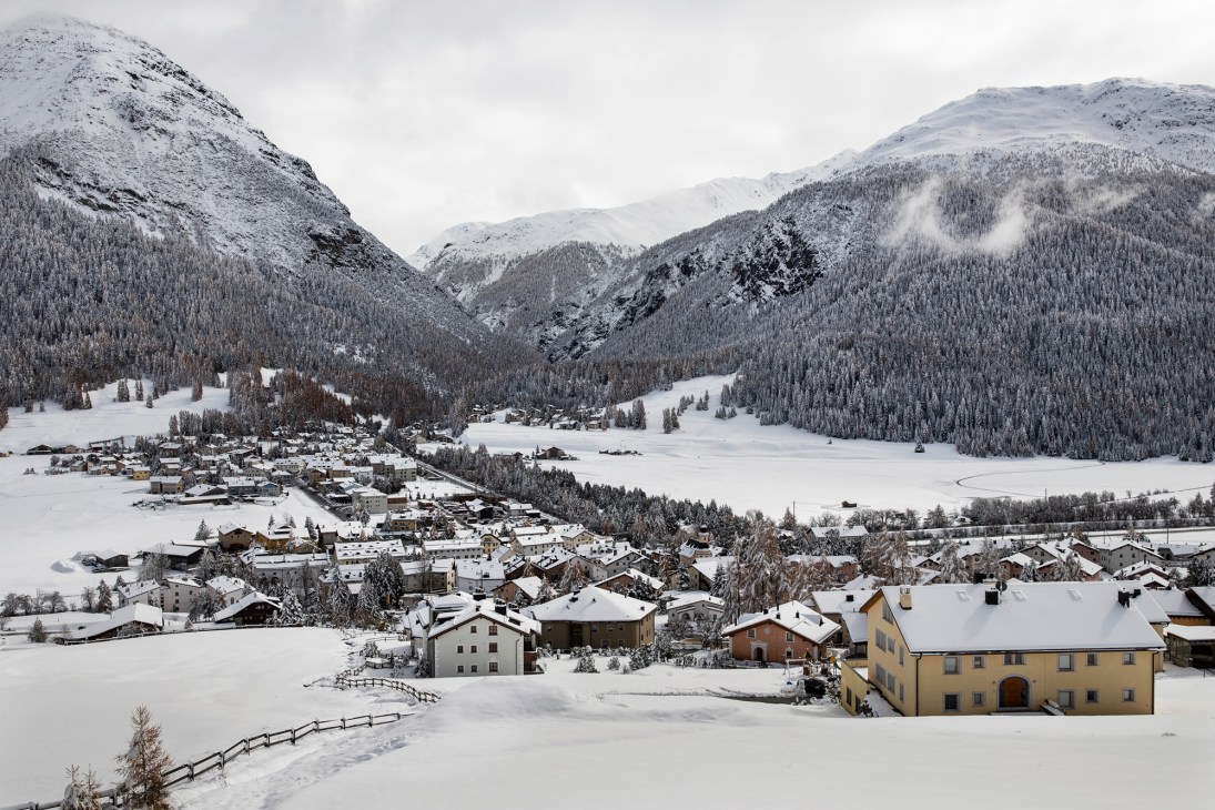 Snow-covered La Punt village with traditional Alpine buildings nestled in the valley