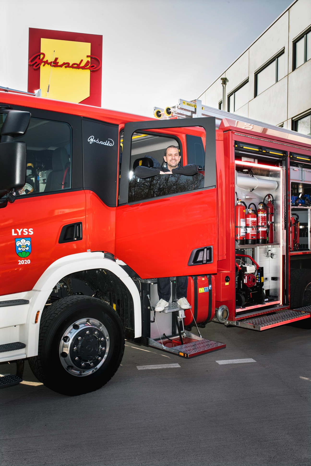 Designer Lukas Scherrer standing on the back of a red Brändle Neorosso fire engine