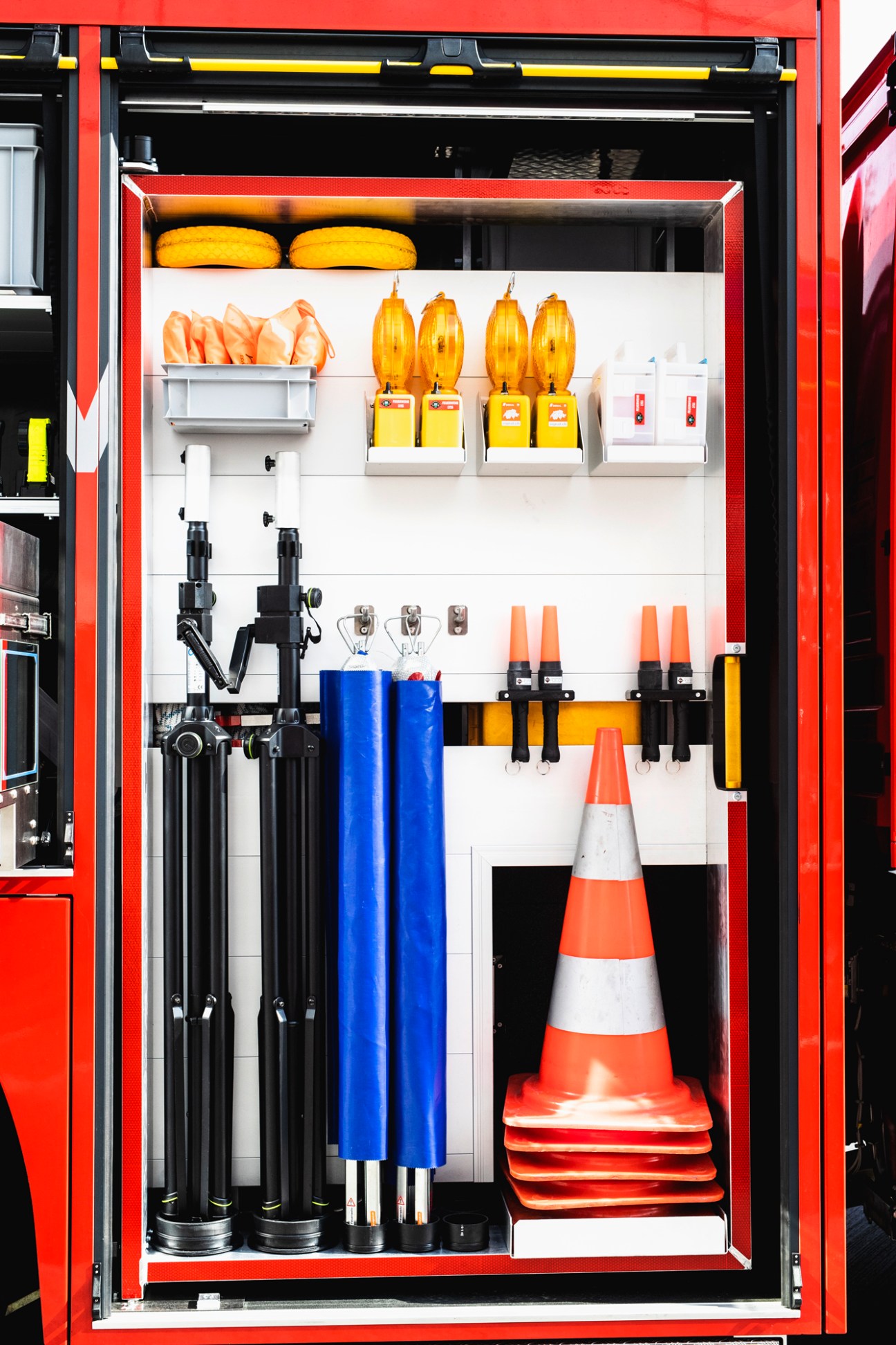Organized storage compartment showing firefighting tools, axes, and equipment neatly arranged