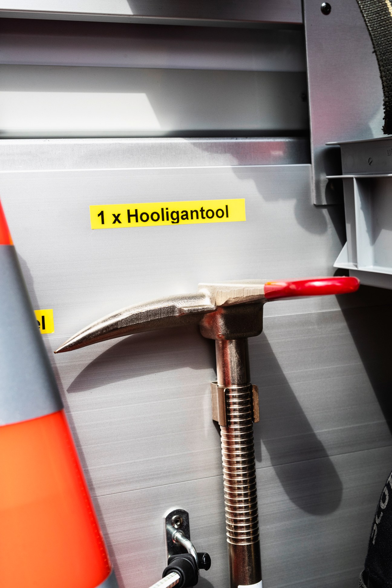 Yellow label reading '1 x Hooligantool' above a red-handled hammer-like tool in a fire engine compartment