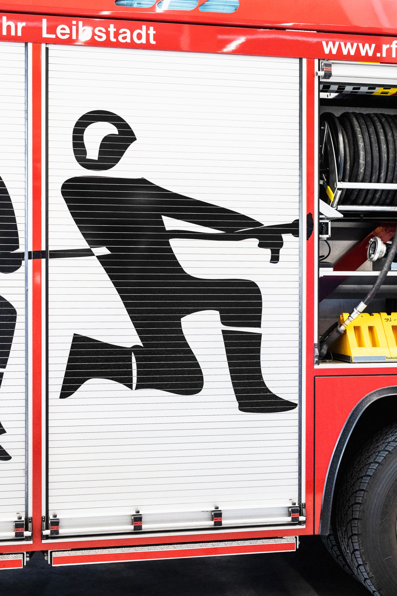 Black silhouette of a person on white rolled door of a red fire engine