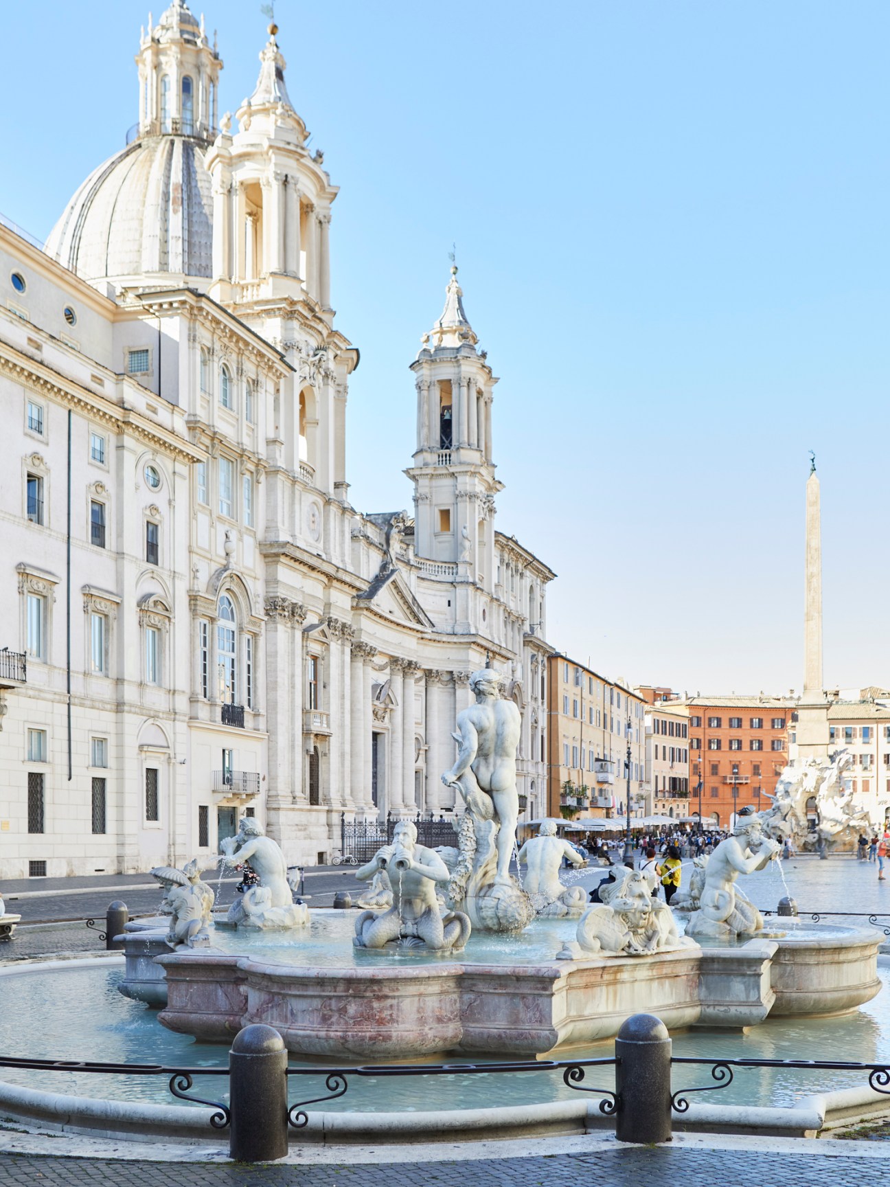 Baroque fountain with white marble statues in historic Italian piazza with church and buildings