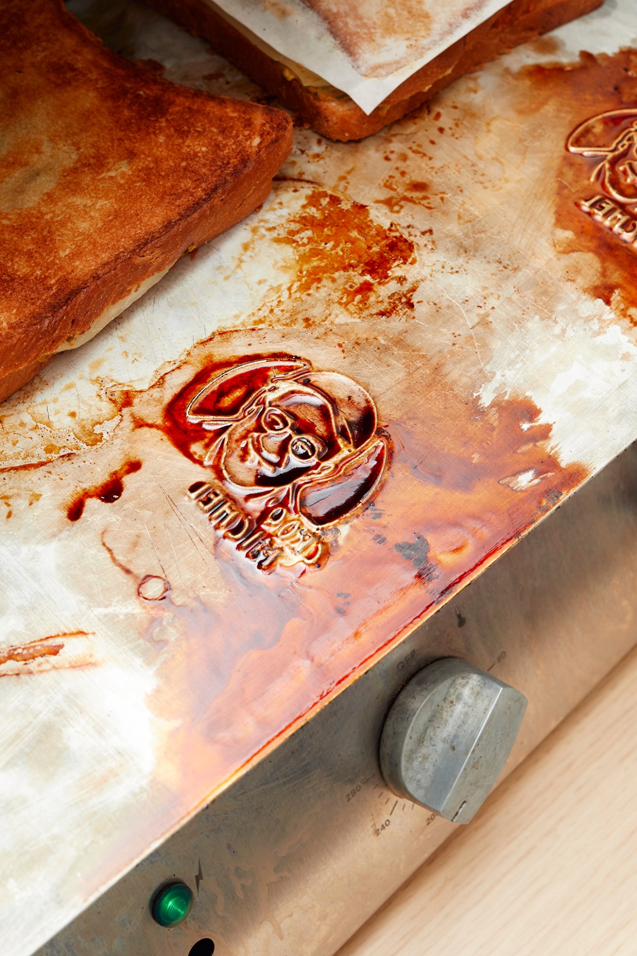 Close-up of croque monsieur showing embossed logo with chef's smiling face