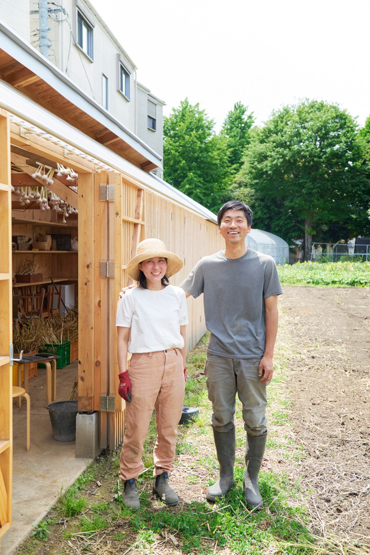 Yu Tominaga and Mayumi Kawaguchi standing together at their urban farm with a wooden storage shed behind them