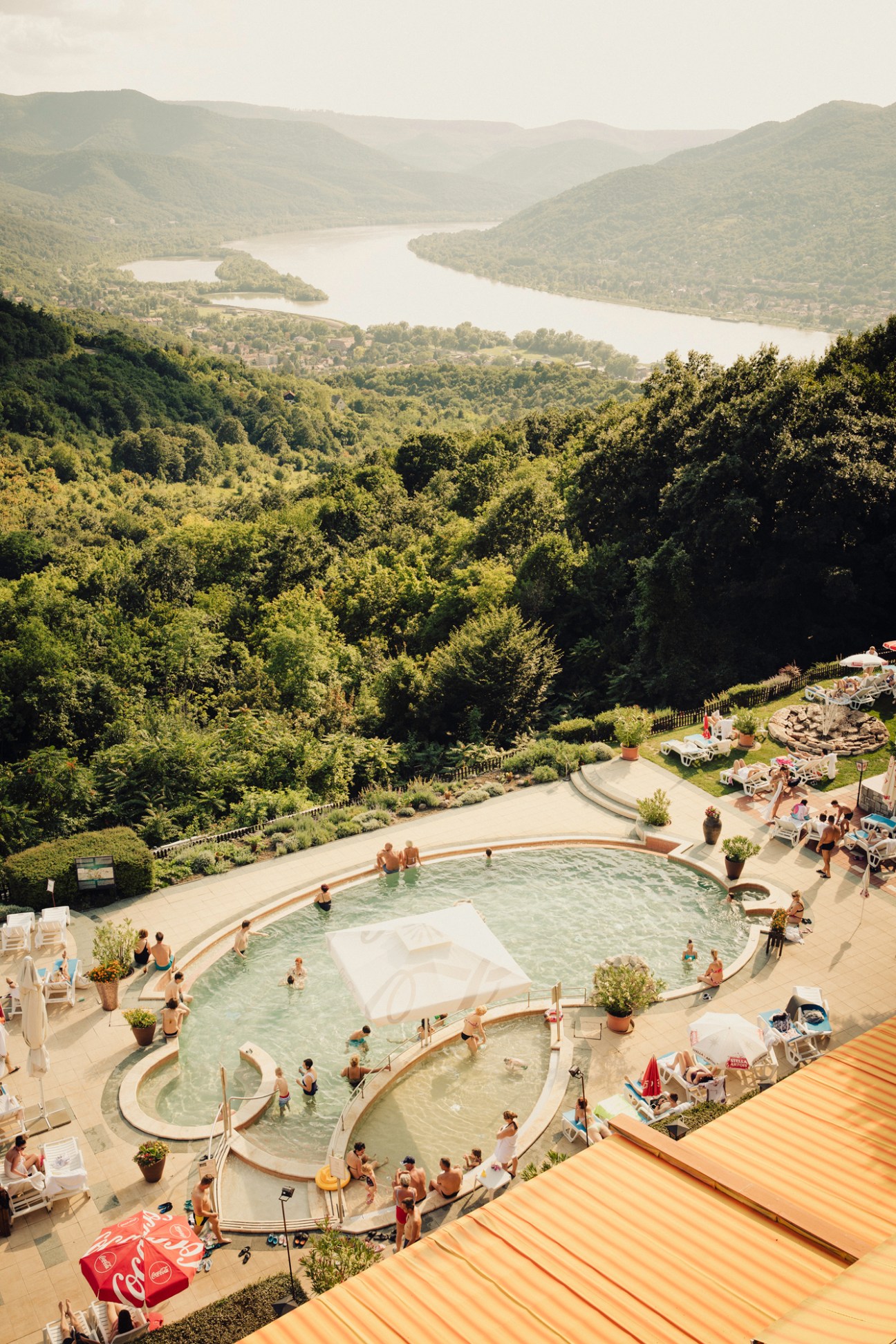 Outdoor swimming pools with terraced levels overlooking the Danube Bend with forested hills in background