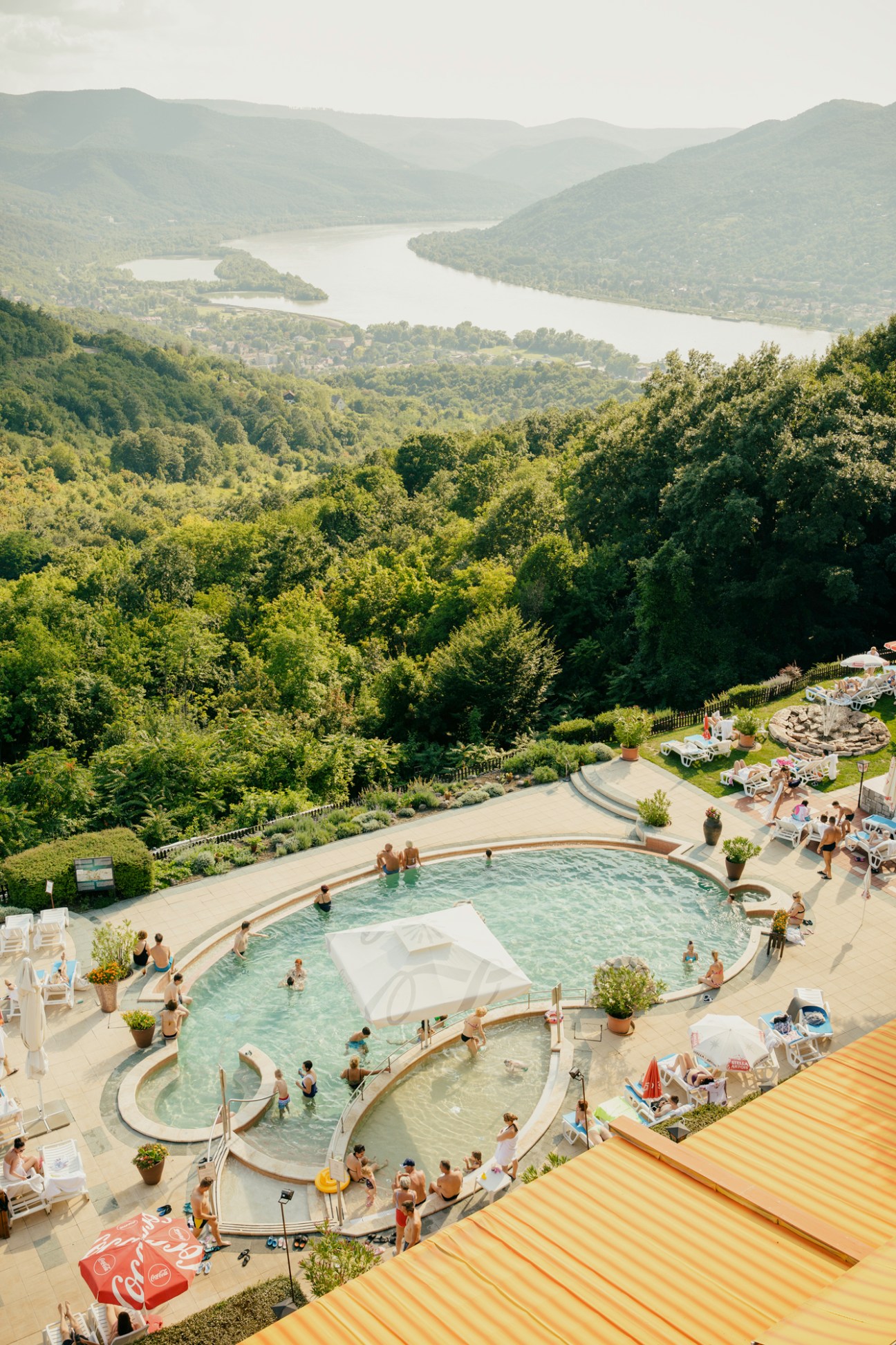 Aerial view of Hotel Silvanus pool overlooking the Danube river valley with forested hills.